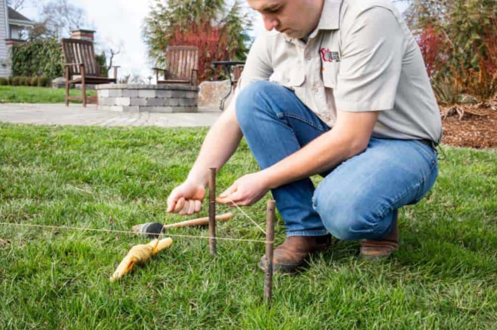 Marking Gazebo Site - String Line Closeup Person marking out square gazebo base with string lines and wooden stakes in backyard